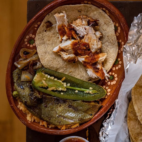 Chicken taco with salsa, grilled peppers, onions, and rice on a rustic plate.
