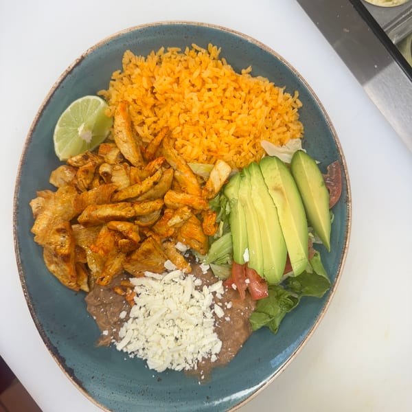 A plate of Mexican food with chicken, rice, refried beans, avocado, and a lime wedge.